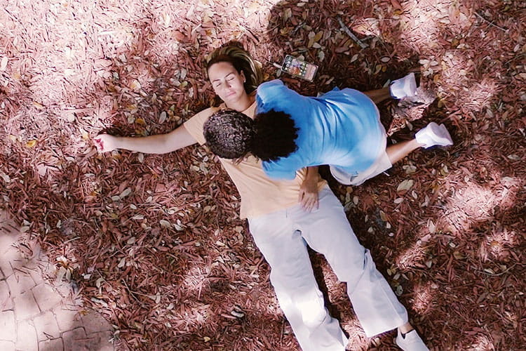 Overhead view of an unconsious person laying on the ground with a concerned bystander performing CPR