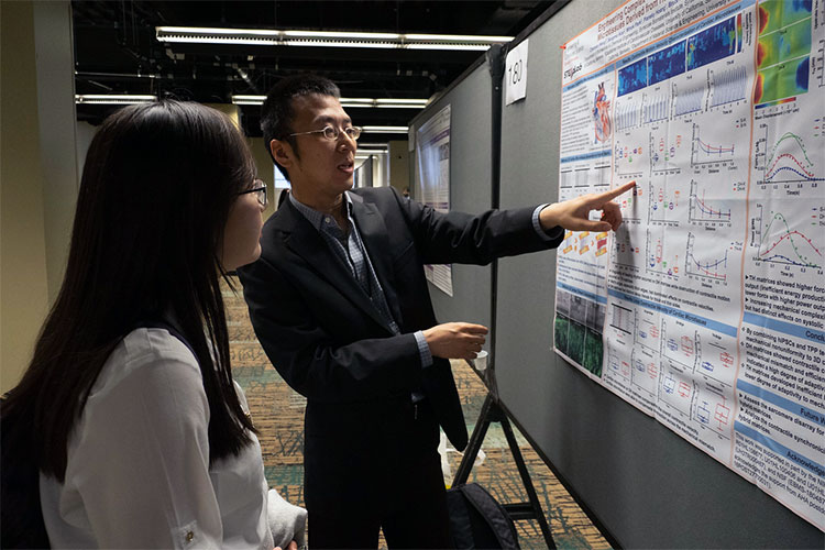 A summit attendee listens to a poster author explain his science.