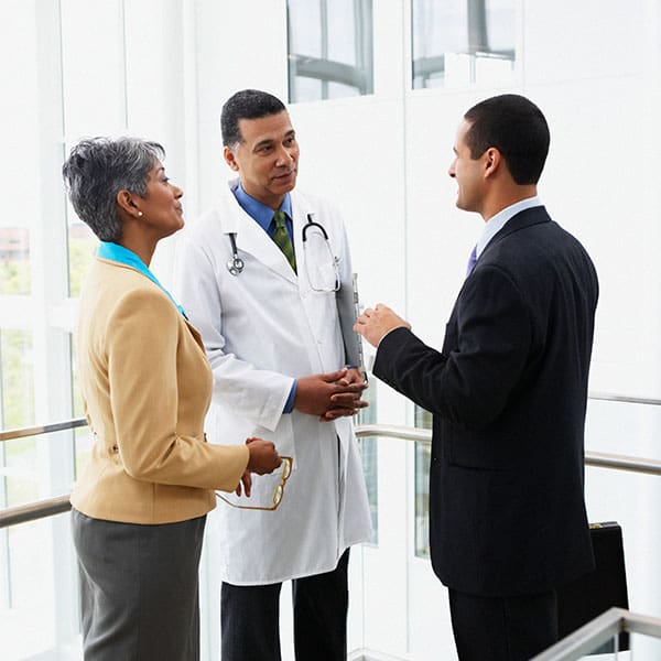a male doctor and women hosptial administrator talking to a male buisiness person