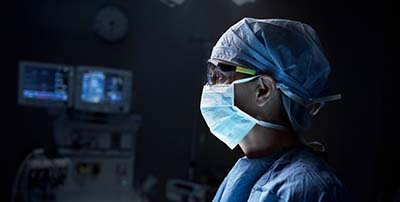 Doctor in mask looking off camera in dark surgery room