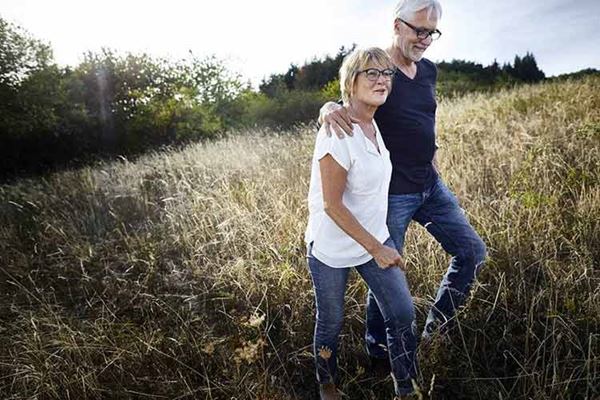 A couple walks in a field of long grasses.