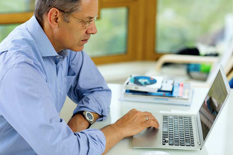 A man looks at information on a laptop in his home.