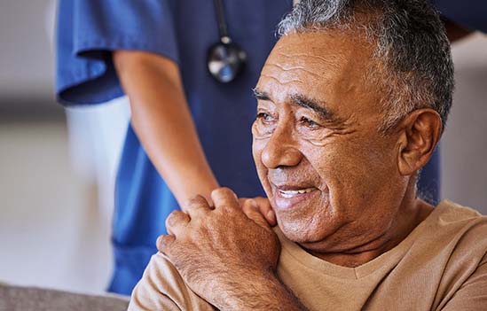 An older gentleman holding the hand of a healthcare professional.