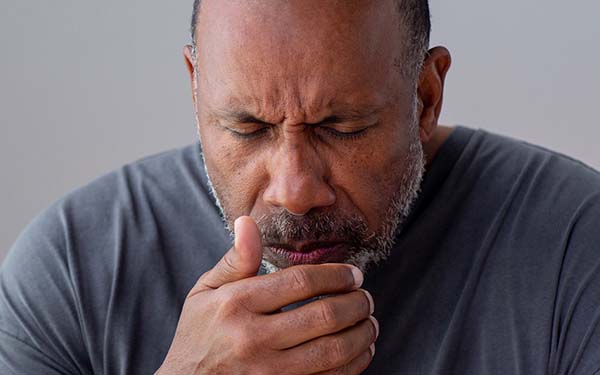 黑人男性咳嗽时捂住嘴。