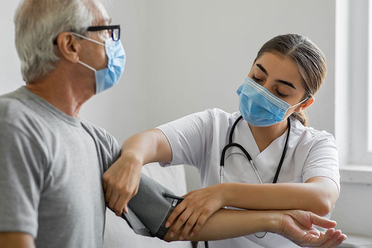 A female home healthcare worker checks a man's blood pressure.