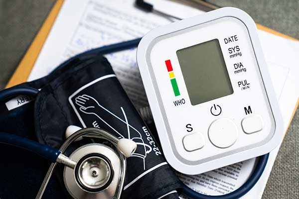Photo of a digital blood pressure cuff and stethoscope, both resting on a piece of paper