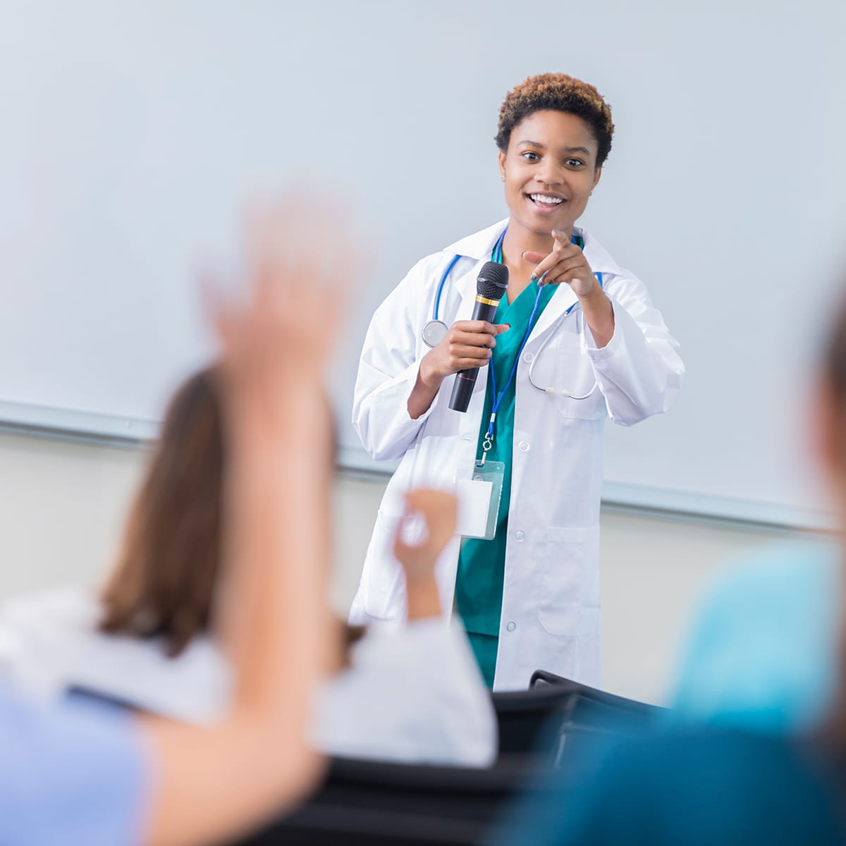 Women doctor teaching with a student raising her hand.