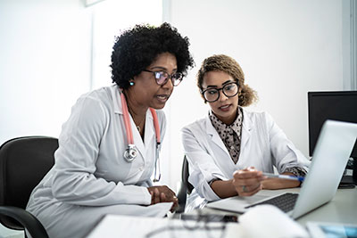 Two female doctors looking at a laptop.