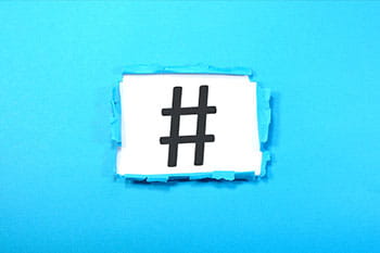 A hashtag symbol with torn blue paper edge surrounding it.