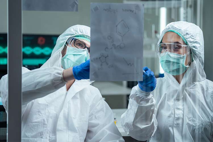 Two lab workers analyzing the coronavirus structure while wearing wearing PPE.