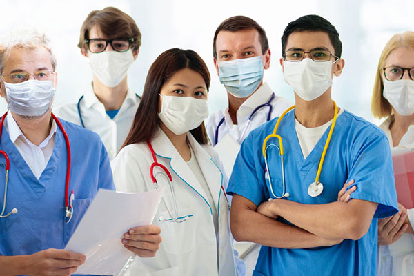 Several healthcare professionals wearing masks, standing together facing camera.