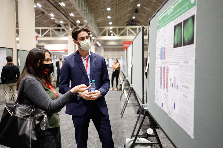 Two investigators discuss the science presented during a poster hall session at the International Stroke Conference 2022.