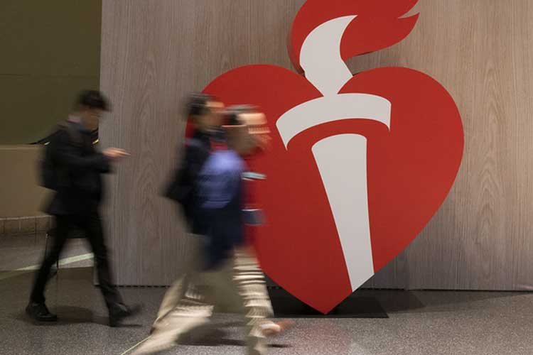 International Stroke Conference attendees walk past a large heart and torch sign on in the convention center.