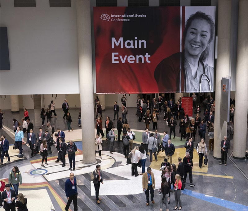 A photo looking down into a convention lobby, where attendees are walking beneath a sign reading, "International Stroke Conferece Main Event."