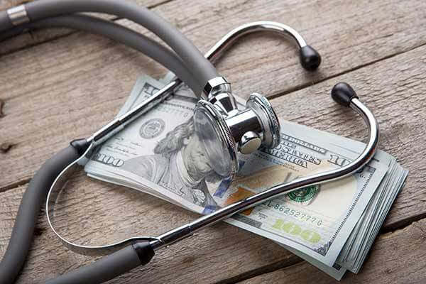 Stethoscope resting on top of pile of cash
