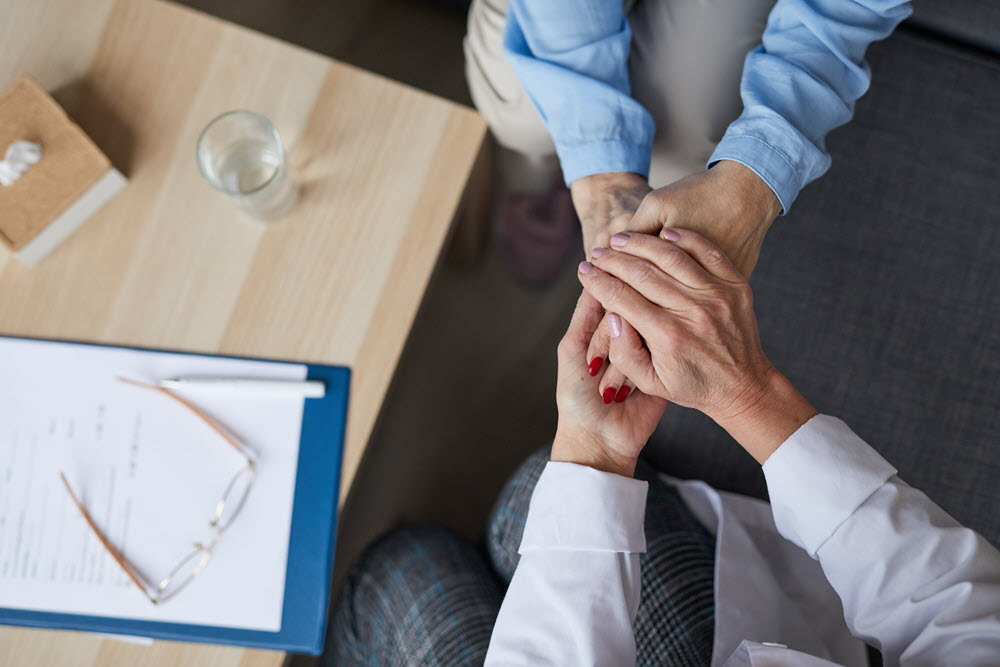 Caring doctor holding hands with a patient