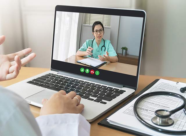 Two female doctors discuss medicine via teleconference on computer.