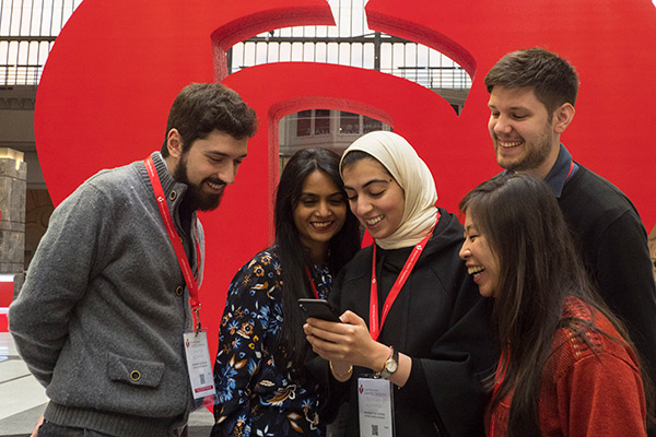 Scientific Sessions attendees looking at a phone in front of giant Heart and Torch stature