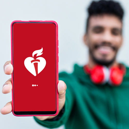 Photo of a young Hispanic man holding out a mobile phone with the AHA logo on the screen.