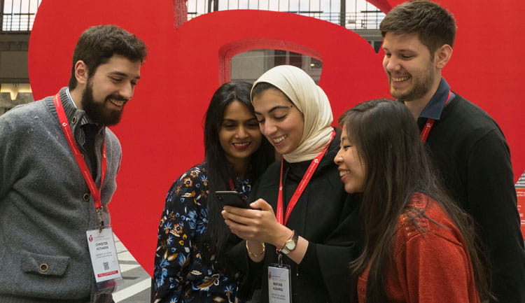 A group of five people from all different backgrounds smile at a photo on a phone. Taken at Scientific Sessions.