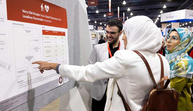 Attendees discuss a poster presentation during #AHA23 in Phladelphia.