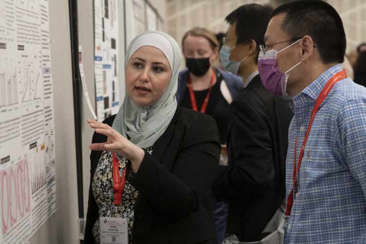 Two attendees discuss the science on a poster presentation during Vascular Discovery 2022.