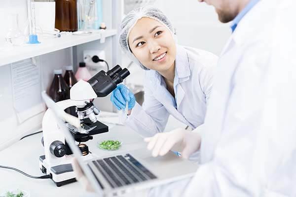 scientists discussing data received from microscope in a laboratory