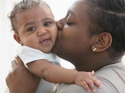 Image of Black woman kissing her baby
