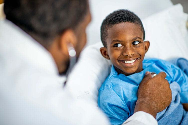 boy smiling while doctor checking his heartbeat with a stethoscope