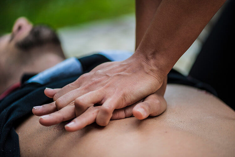 person performing CPR on a man outside.