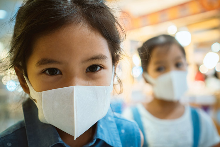 Cute Asian child girl wearing protection mask to against air smog pollution with PM 2.5