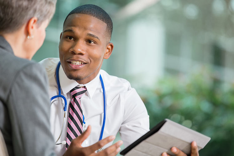 Young doctor discussing hospital policy with senior patient in office