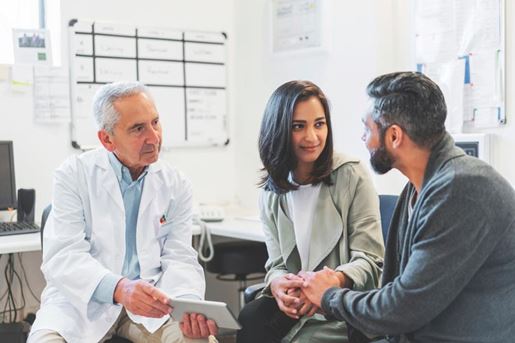 doctor using a digital tablet while talking to a couple