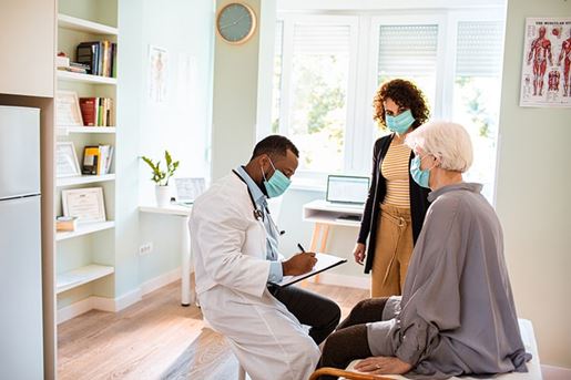 Doctor meeting with a senior patient and her daughter in his office.