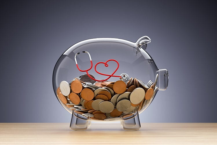 Glass piggy bank with money and a red stethoscope twisted into a heart.