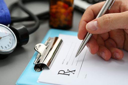 male doctor's hand writing prescription to patient