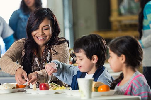 Mother and children eating meal in food bank soup kitchen