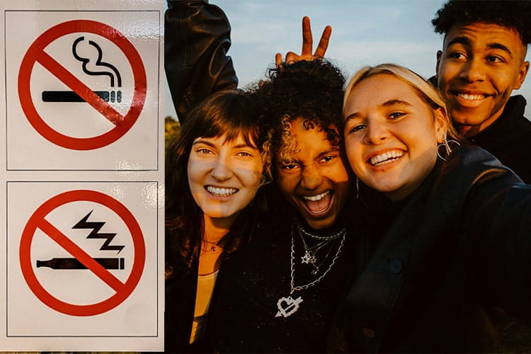 A group of cheerful friends taking selfies next to no vaping sign outdoors during sunset