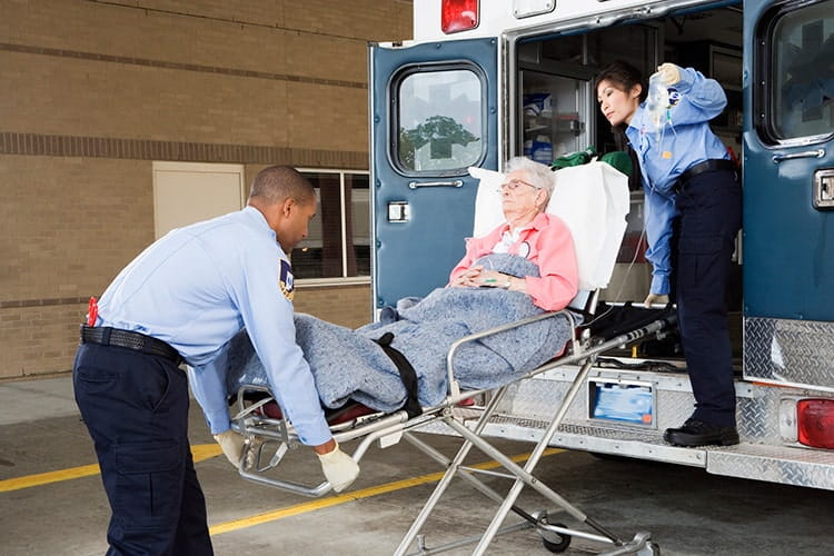 Two paramedics putting senior woman into ambulance.