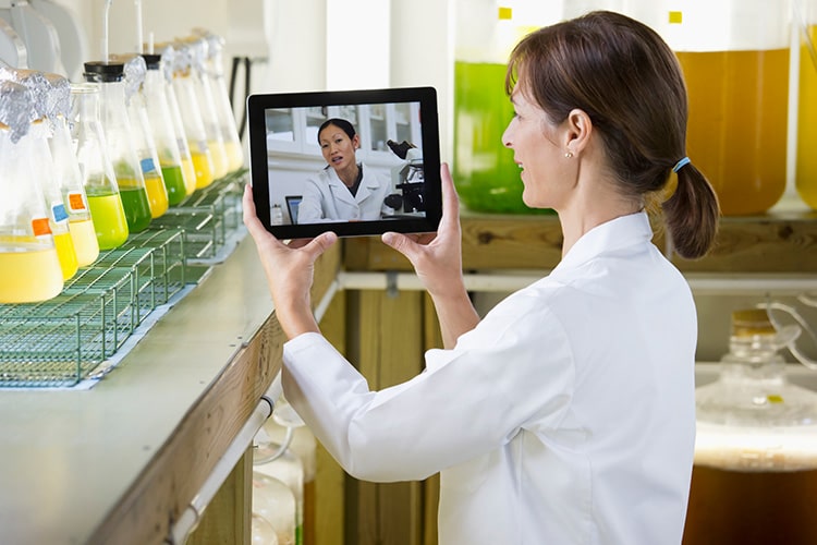 Scientists video conferencing on digital tablet in laboratory