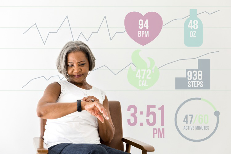 An active African American senior woman checks activity level and health status on her smart watch. Heart rate, water consumption, steps taken, activity level and the current time are overlaid in a digitally generated image.