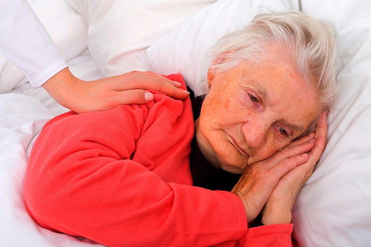 A close-up of a elderly lady laying on her side in bed