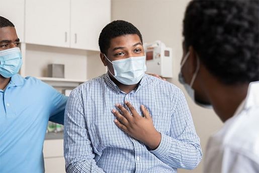 Teenage boy explains symptoms to his doctor during the Covid-19 pandemic
