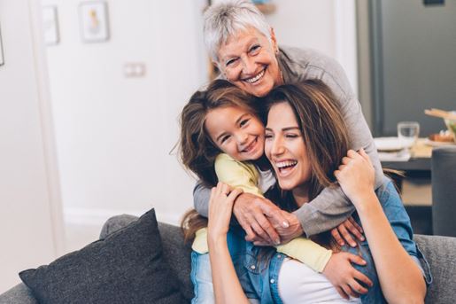 Three generations of women embracign in their living room.