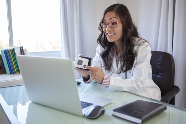 Doctor conducting telehealth instruction via laptop in her office