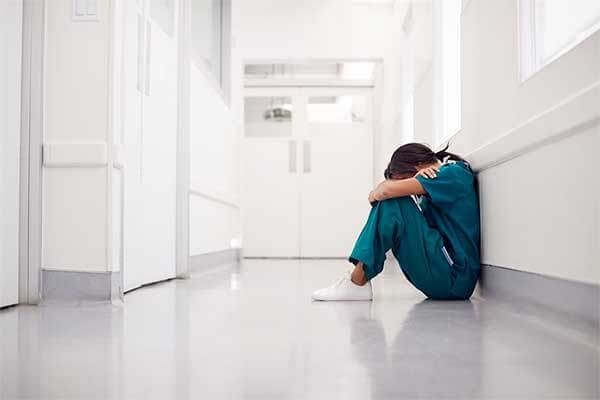Stressed person sitting on floor covering her face