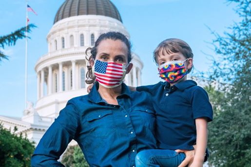 Mature woman posing carrying her son with the State Capitol building in the background.