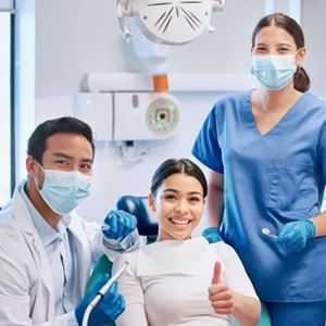 Male dentist with female patient and assistant in dental office