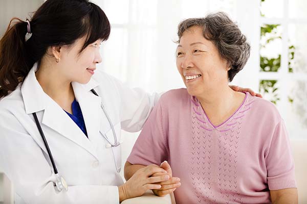 Woman doctor holding hand of senior woman