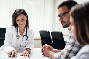 Women doctor reviewing medical records with couple